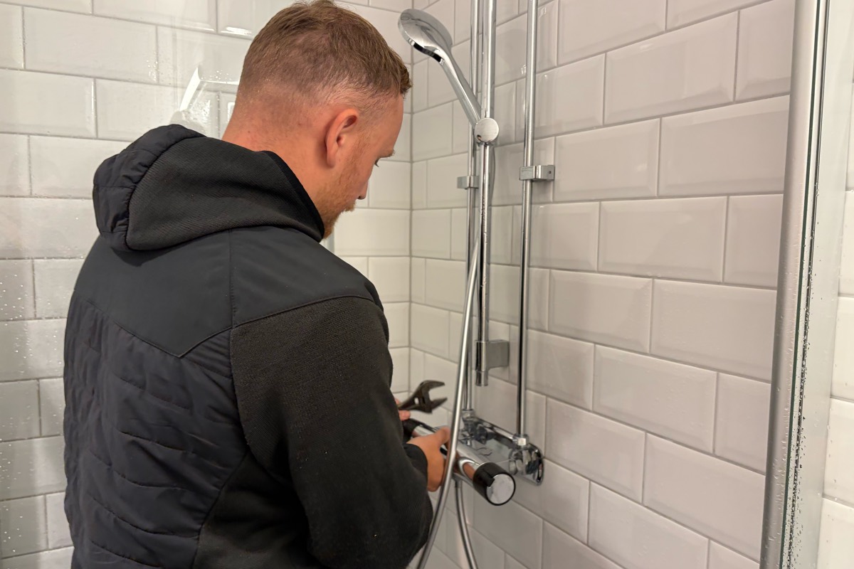 En rörmokare från Fixit monterar en termostatblandare i en dusch